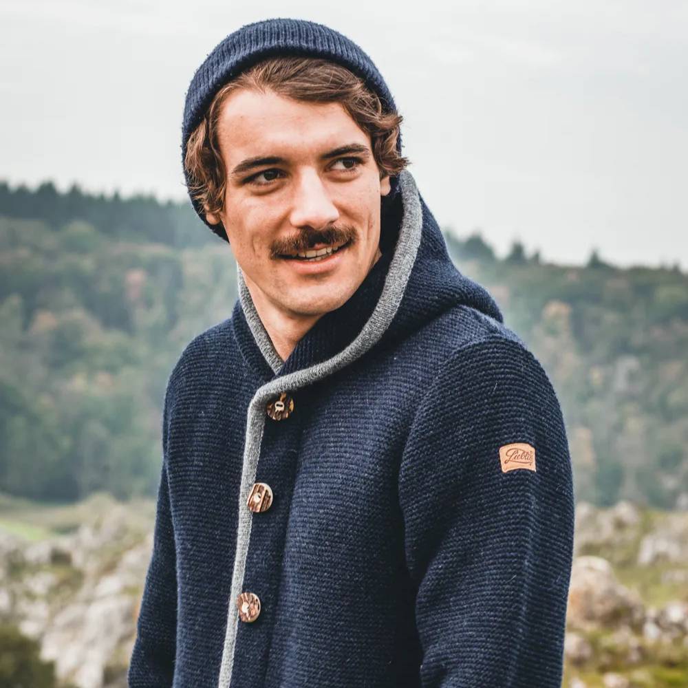 Hoamat Gfui Liebling Janker Tomahs II in navy & rau getragen von einem Mann in den Bergen