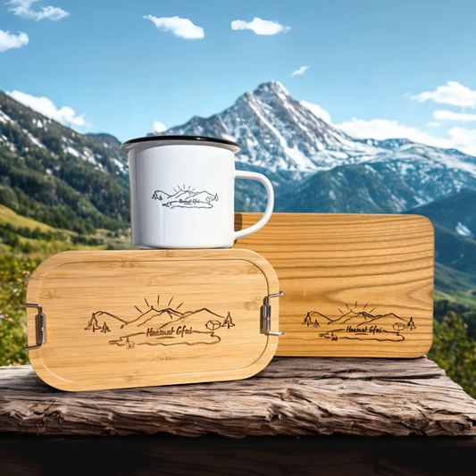Gipfelstürmer Set von HoamatGfui – Brotdose, Brotzeitbrett und Emaille-Tasse vor Bergpanorama